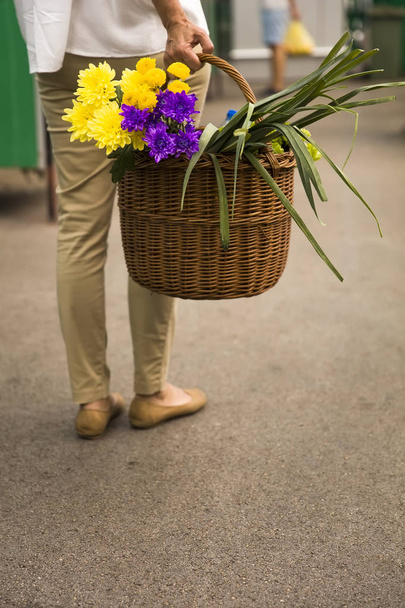 Mujer sostiene una cesta con flores en el mercado
 - Foto, imagen