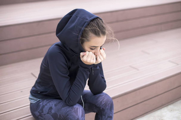 Портрет обеспокоенной, грустной и депрессивной молодой женщины сидит снаружи
 - Фото, изображение