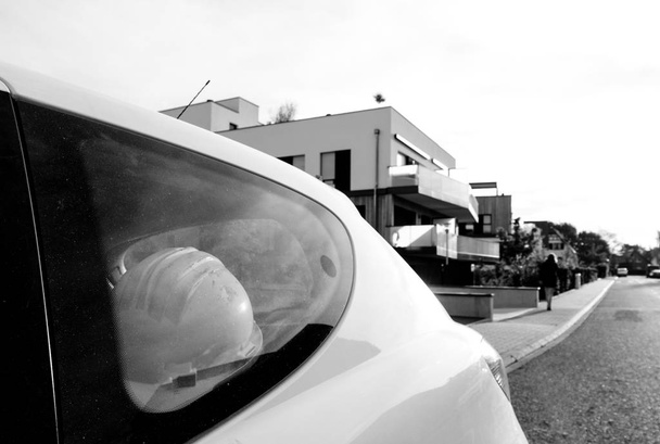 Capacete de proteção no carro com arquitetura inspecionando edifício
 - Foto, Imagem