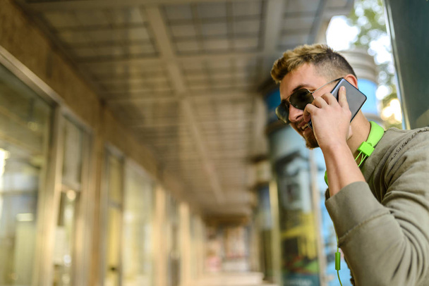 Junger Hipster mit seinem Smartphone in der Stadtstraße - Foto, Bild