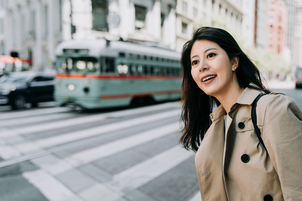 arka planda sürüş trafik otobüs araba araçlar ile zebra yol geçiş için bekleyen gülümseyerek mutlu bir iş kadını. sabah yoğun iş alanında küçük Asya hanım. büyüleyici kolej kız etrafa - Fotoğraf, Görsel
