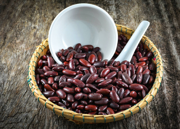 Κόκκινα φασόλια azuki ή κόκκινο φασόλι σπόρων σιτηρών στο καλάθι και Κύπελλο κουτάλι σε ρουστίκ ξύλινα φόντο - Φωτογραφία, εικόνα
