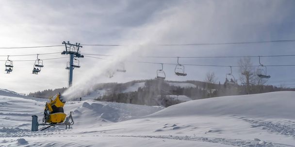 Schneeerzeuger gegen Skilifte und bewölkten Himmel in Uta - Foto, Bild