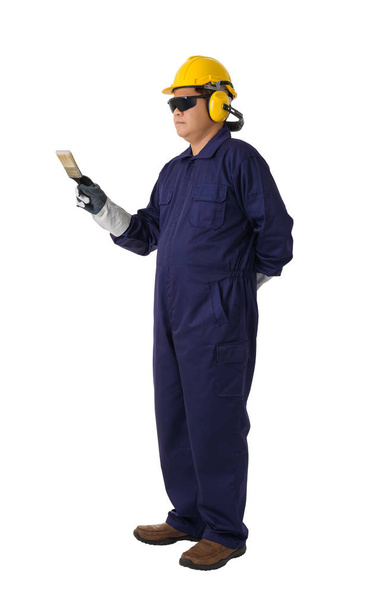 Полный портрет рабочего в механическом комбинезоне держит кисть краски со шлемом, наушниками, защитными перчатками и защитными очками, изолированными на белом фоне
 - Фото, изображение