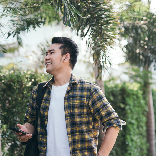 Happy Asian tourist holding smart phone for find his target, lifestyle concept. - Fotó, kép