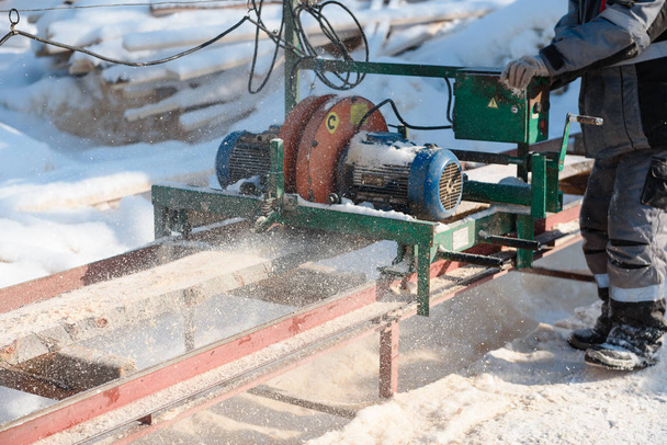 Sawing boards on the sawmill. Cook lumber in winter. Work on the sawmill. Sawing boards in winter. - Foto, Bild