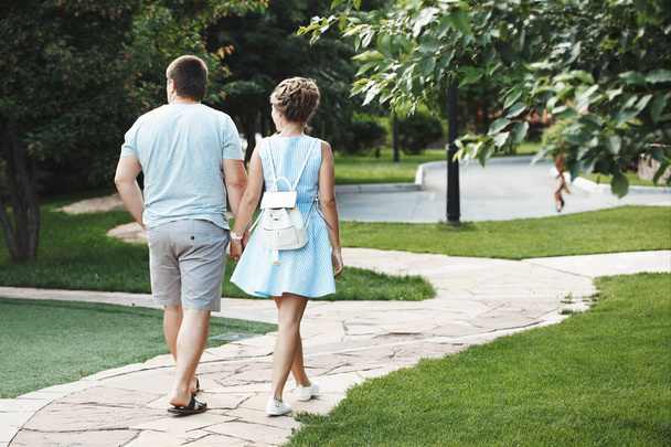 вид ззаду пари тримає руки під час прогулянки по стежці в парку влітку
 - Фото, зображення