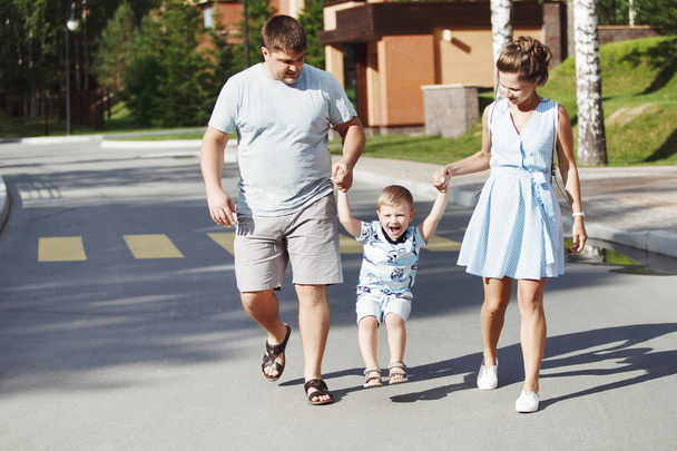 happy family walking along sidewalk in park, focus on foreground - Фото, изображение