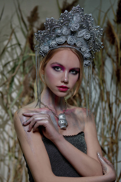 girl in silver makeup and red lips in silver headdress on nature background - Фото, изображение