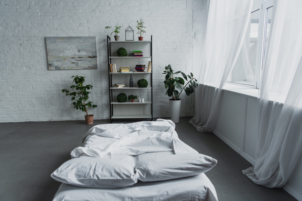 modern interieur van slaapkamer met rek, planten, bed, bakstenen muur en kopie ruimte - Foto, afbeelding