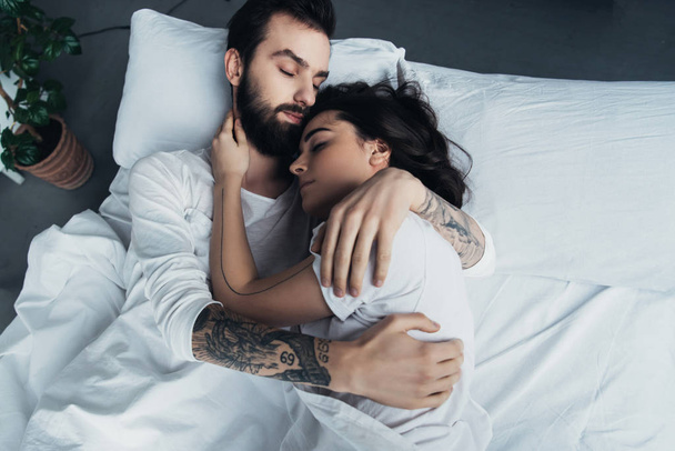 piękne młode tatuażem, para Ogarnięcie podczas snu w łóżku - Zdjęcie, obraz