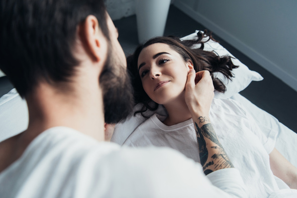 homme tatoué barbu embrassant belle femme à la maison au lit
 - Photo, image