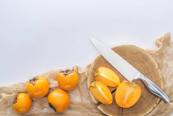 orange cut and whole persimmons on cutting board with copy space - Valokuva, kuva
