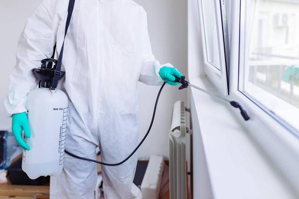 Exterminator in work wear spraying pesticide with sprayer. - Photo, Image