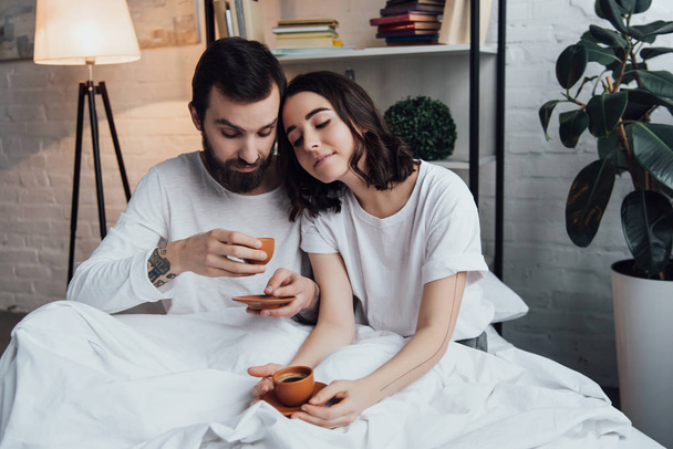 красивая молодая пара лежит в постели с кофе по утрам
 - Фото, изображение