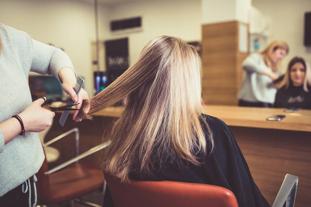 Zbliżenie kobiety w salonie fryzjerskim coraz jej włosy cięte przez fryzjera. - Zdjęcie, obraz