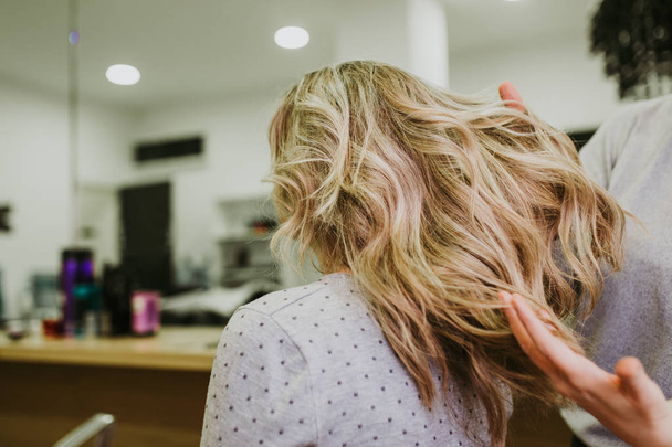 Beautiful hairstyle of young woman after drying hair and making highlights in hair salon.  - 写真・画像