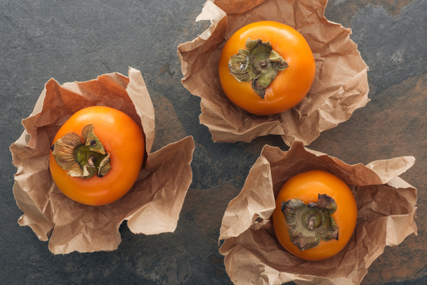 top view of orange and whole persimmons in paper  - Foto, afbeelding