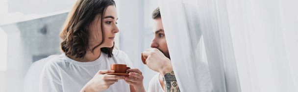 beautiful young couple drinking coffee in morning and looking at each other - Fotó, kép