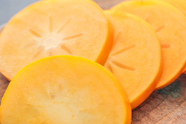 close up of orange cut persimmons slices on wooden board - Fotografie, Obrázek