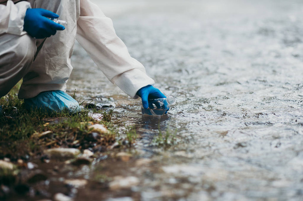 Wissenschaftler in Schutzanzügen entnehmen Wasserproben aus dem Fluss. - Foto, Bild