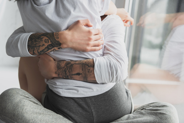 rajattu näkymä tatuoitu mies intohimoisesti halaamalla nainen kotona
 - Valokuva, kuva