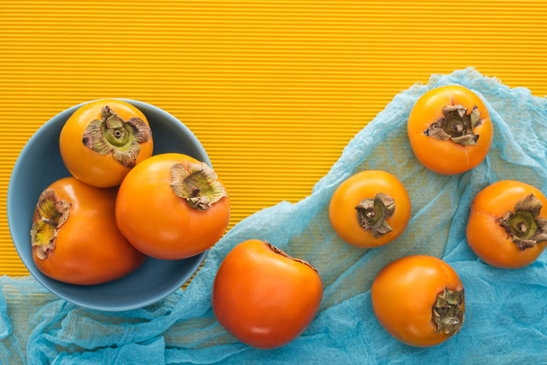 Ansicht ganzer orangefarbener Kaki auf blauem Teller und Tuch  - Foto, Bild