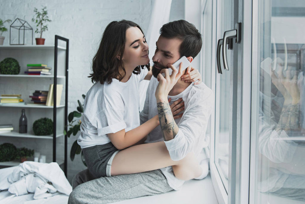 hermosa mujer abrazando hombre hablando en el teléfono inteligente en casa
 - Foto, imagen