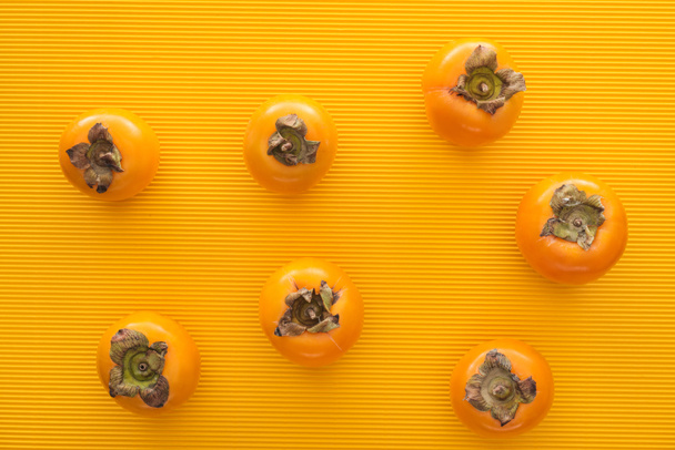 top view of whole orange persimmons on yellow background  - Fotó, kép