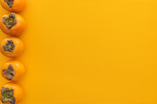 bovenaanzicht van Oranje kaki op gele achtergrond met kopie ruimte - Foto, afbeelding