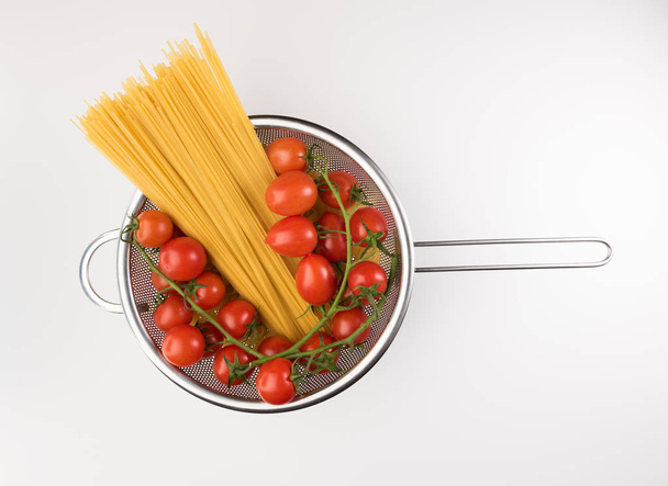 Colander with raw pasta and tomatoes isolated on white background, top view. Flat lay - Fotoğraf, Görsel