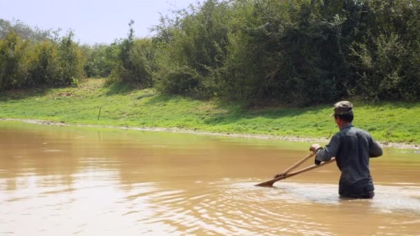 pescador utilizando una cesta de empuje para arrastrar sobre el fondo arenoso del lago donde se capturan las almejas. La cesta de mimbre triangular está unida a un poste de bambú dividido en dos partes
.  - Imágenes, Vídeo