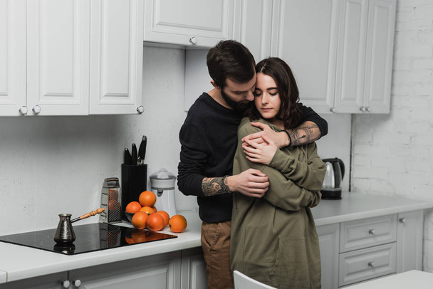 hermosa joven pareja abrazando en kithchen durante el desayuno
 - Foto, imagen