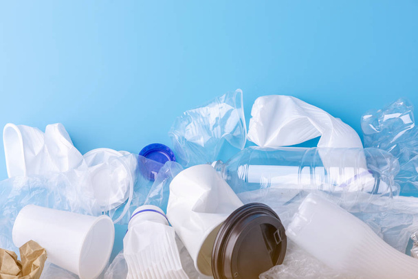 Gebruikte ongesorteerd schoon afval in een stapel. Flessen, zakken en papier op blauwe achtergrond. Concept van milieuvervuiling en Afvalsortering - Foto, afbeelding