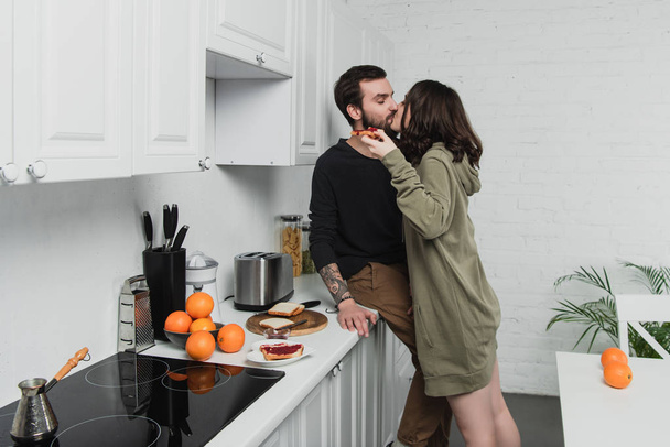 beautiful young romantic couple kissing during breakfast in kitchen - Photo, Image