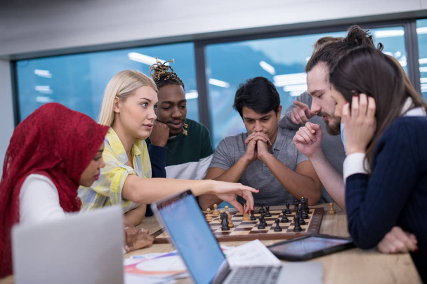a multiethnic group of business people playing chess while having a break in modern startup office - Zdjęcie, obraz