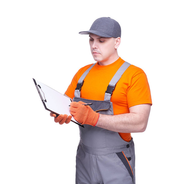 Loader in workwear, profession of the service industry, paper tablet, writing documents, young sports man, cargo transportation, courier in working clothes, worker isolated on white background - Foto, imagen