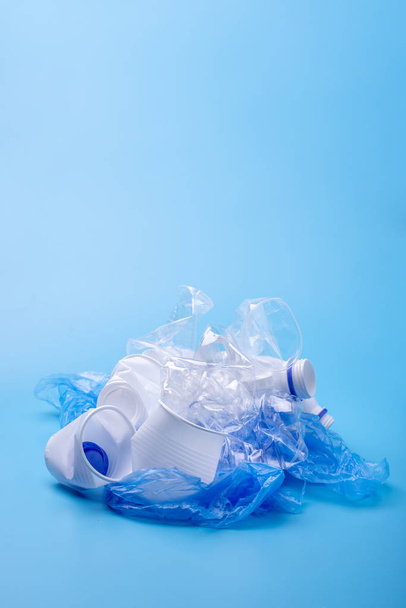 Μεταχειρισμένα σκουπίδια σε μια στοίβα. Μπουκάλια, σακούλες και χαρτί σε μπλε φόντο. Εννοιολογικό διαχωρισμό αποβλήτων. Θέση για κείμενο - Φωτογραφία, εικόνα