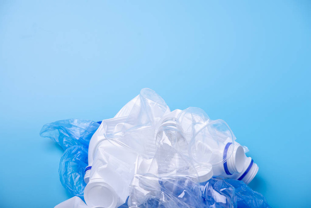 verwendet unsortierten Müll in einem Haufen. Flaschen, Tüten und Papier auf blauem Hintergrund. Konzept Mülltrennung. Platz für Text - Foto, Bild