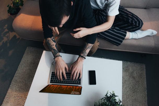 Çift oturma ang evde online ticaret Web sitesi ile dizüstü bilgisayar kullanırken sarılma görünümünü kırpılmış  - Fotoğraf, Görsel