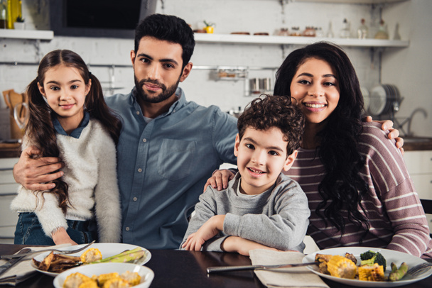 cheerful latino family smiling while looking at camera during lunch - Fotoğraf, Görsel