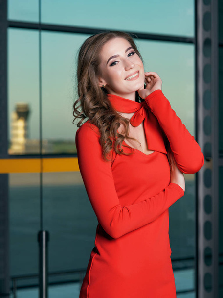 young beautiful woman wearing red dress posing in airport scene - Foto, afbeelding