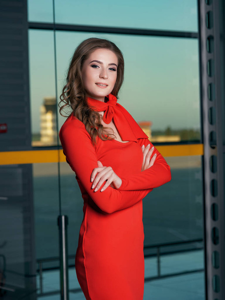 young beautiful woman wearing red dress posing in airport scene - Photo, image