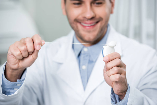 selective focus of dental floss in hands of cheerful dentist - Photo, Image