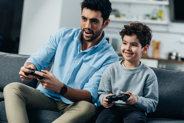 ευτυχισμένος Λατινική πατέρας και γιος παίζει βίντεο παιχνίδι στο σπίτι - Φωτογραφία, εικόνα