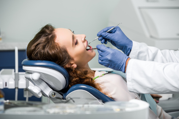 vista ritagliata del dentista in guanti di lattice esaminando i denti della donna in clinica dentale
 - Foto, immagini