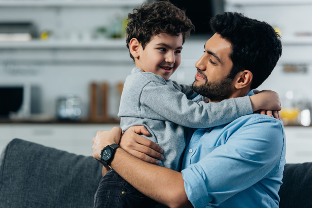 happy latin father hugging cute son at home - Foto, Imagen