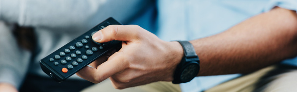cropped view of man holding remote control in hand  - Photo, Image