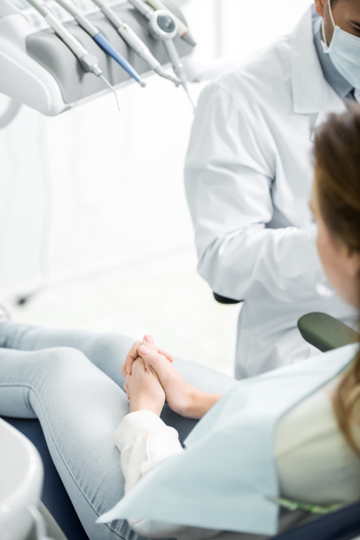 foco seletivo da mulher sentada na cadeira perto do dentista
  - Foto, Imagem
