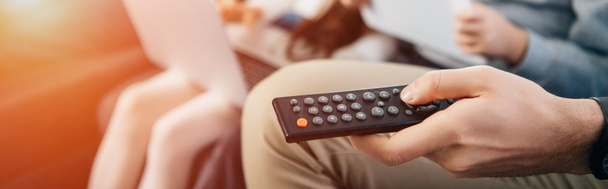 cropped view of man holding remote control in hand near family - Photo, Image